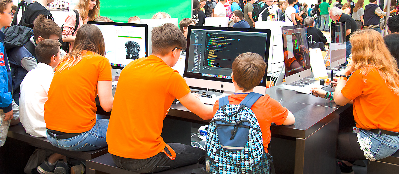 Schüler der Dr. Buhmann Schule & Akademie zeigen jungen Besuchern kreative Arbeit am Rechner.